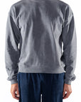 Person wearing a gray sweatshirt and navy day pants on a white background