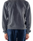 Person wearing a dark gray sweatshirt and navy day pants on a white background