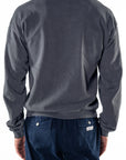 Back view of a person wearing a dark gray sweatshirt and navy day pants on a white background