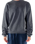 Woman wearing a dark gray sweatshirt and navy day pants on a white background
