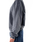 Side view of a woman wearing a gray sweatshirt and navy day pants on a white background