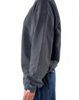 Side view of a person wearing a dark gray sweatshirt and navy day pants on a white background