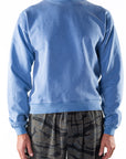 Person wearing a blue sweatshirt and ocean tiger camo day pants on a white background
