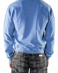 Back view of a person wearing a blue sweatshirt and ocean tiger camo day pants on a white background