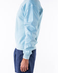Person wearing a turquoise sweatshirt and navy day shorts on a white background