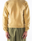 Person wearing a sunrise yellow sweatshirt and army green day pants on a white background