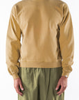 Person wearing a sunrise yellow sweatshirt and army green day pants on a white background