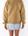 Woman wearing a sunrise yellow sweatshirt and denim mini skirt on a white background