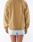 Back view of a woman wearing a sunrise yellow sweatshirt and denim mini skirt on a white background