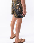 Side back view of a person wearing real tree camo day shorts on a white background.
