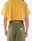 Woman wearing a sunrise yellow crop t-shirt and army green day pants on a white background