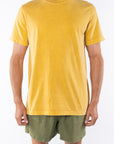 Person wearing a sunrise yellow beach t-shirt and army green day shorts on a white background