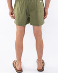 Back view of army green day pants worn by a person on a white background