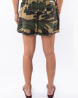 Back view of a woman wearing camouflage day shorts on a white background