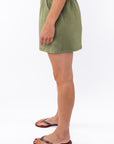 Side view of a woman wearing army green day shorts on a white background