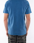 Back view of a man wearing a teal beach t-shirt with ocean tiger camo day pants on a white background