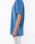 Side view of a woman wearing a beach blue t-shirt with light denim jeans on a white background
