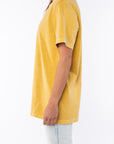 Side view of a woman wearing a sunrise yellow beach t-shirt and light denim jeans on a white background