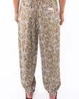 Back shot of a woman wearing leopard printed pants on a white background.