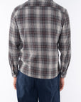 Back shot of man wearing a lightweight flannel Plaid shirt in Black/Red with navy pants.