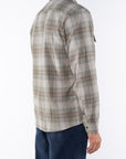 Man wearing a lightweight flannel plaid shirt in Green/Red with navy pants on a white background.