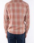 Back shot of a man wearing a lightweight flannel Plaid shirt in Orange/Blue with navy pants on a white background.