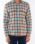 Man wearing a lightweight flannel Plaid shirt in Green/Orange with navy pants.