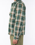 Side shot of a man wearing Bucky Flannel Over shirt in Green/Brown with army green day pants.