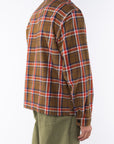 Side back shot of a man wearing Bucky Flannel Over shirt in Brown/Red with army green day pants