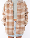 Woman wearing a flannel Split Hem Shirt Jacket in Beige/White Plaid with a crewneck Tank in cream and Denim mini Skirt on a white background.