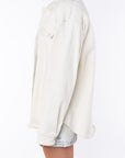 Side shot of a woman wearing Bucky Split Hem Shirt Jacket in Beige with Denim Day Skirt.