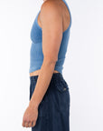 Side shot of a woman wearing Scallop Tank in Blue Wave and navy day pants.