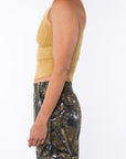 Side shot of a woman wearing Scallop Tank in Sunrise Yellow with Real Tree camo day pants