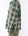 Side shot of a woman wearing Bucky Flannel Over shirt in Green/Brown with army green day pants.