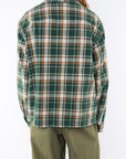 Back shot of a woman wearing the Bucky Flannel Over shirt in green/brown and army green day pants.