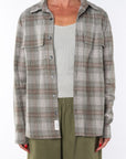 Woman wearing a lightweight flannel plaid shirt in green/red over a v-neck Tank in cream with army green pants on a white background
