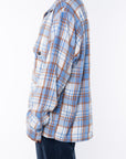 A side shot of a woman wearing the Bucky Flannel Over shirt in blue/tan with navy day pants.