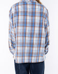 Back shot of a woman wearing the Bucky Flannel Over shirt in blue/tan with navy day pants.