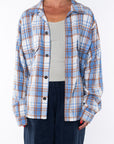 Woman wearing the Bucky Flannel Over shirt in blue/tan with Surf Tank in Sandstone and navy day pants.