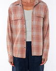 Woman wearing a lightweight flannel plaid shirt in orange/blue over a v-neck Tank in cream with navy pants on a white background