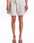 Woman wearing light gray french terry day shorts on a white background