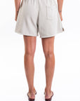 Back view of a woman wearing beige shorts on a white background