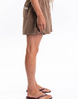 Side view of a woman wearing brown french terry day shorts on a white background