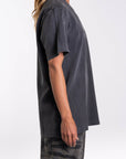Side view of a woman wearing a dark gray t-shirt and camouflage pants on a white background