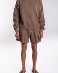 Person wearing a brownstone french terry sweatshirt and day shorts set on a white background.