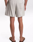 Back view of a man wearing light gray french terry day shorts on a white background