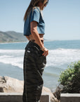 woman at beach parking lot. she is wearing beach crop tee in teal with ocean tiger camo day pants.