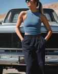 woman leaning on a truck wearing scallop tank in blue wave with navy day pants
