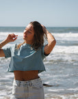 woman wearing beach crop t-shirt in ocean with denim skirt at the beach