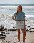 woman wearing beach crop t-shirt in ocean with denim day skirt on a beach